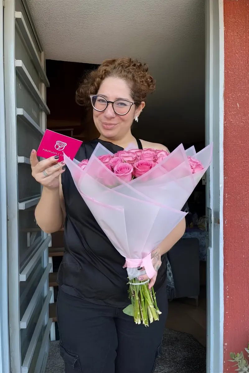 Cliente feliz recibiendo un ramo de rosas rosas premium en Puebla centro.